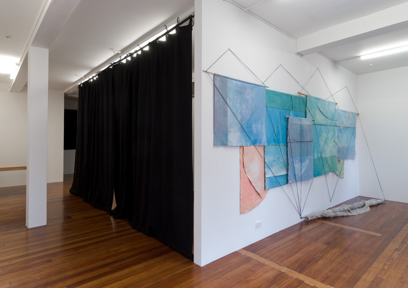 Image: Emma Fitts, From heat to translucence / your mineral touch (installation view), 2023. Weathered canvas, felted wool, aluminium and wooden rods, fabric ties. Photo by John Collie.
