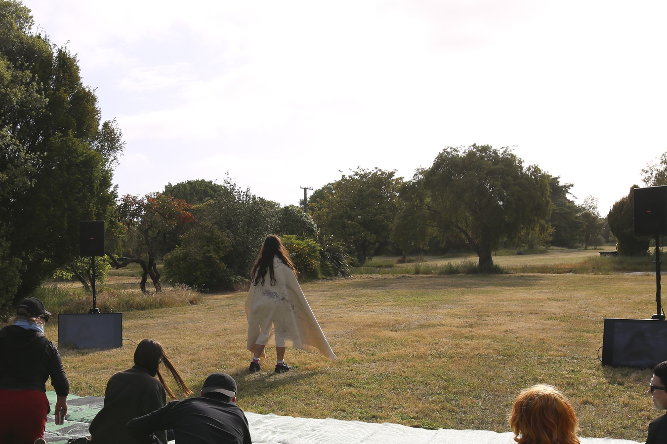 Ella standing with her back to the audience with her canvas draped over her shoulders, she's facing the tree that stood in her front yard.