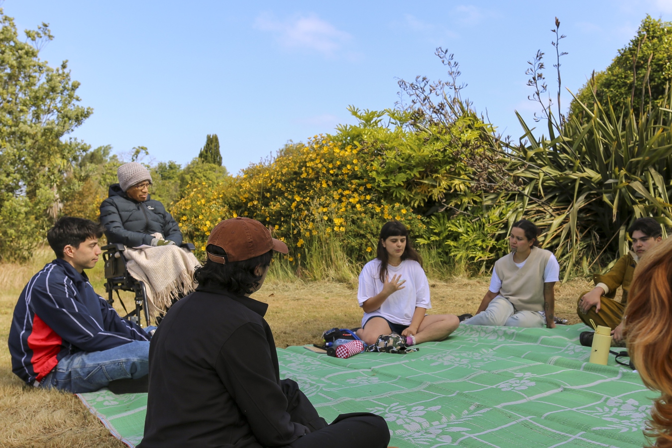 Ella guiding the workshop: Body of Remembering. Everyone sat together in the shade.