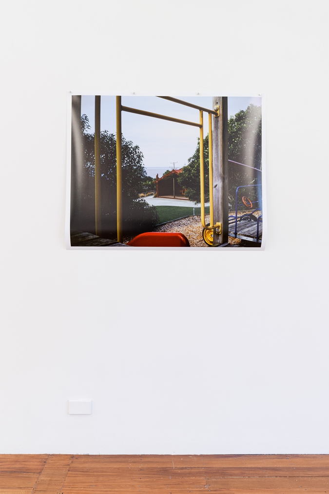 artwork, photograph titled anamata, large format photograph featuring looking through a brightly covered playground at a marae and the ocean on the horizon