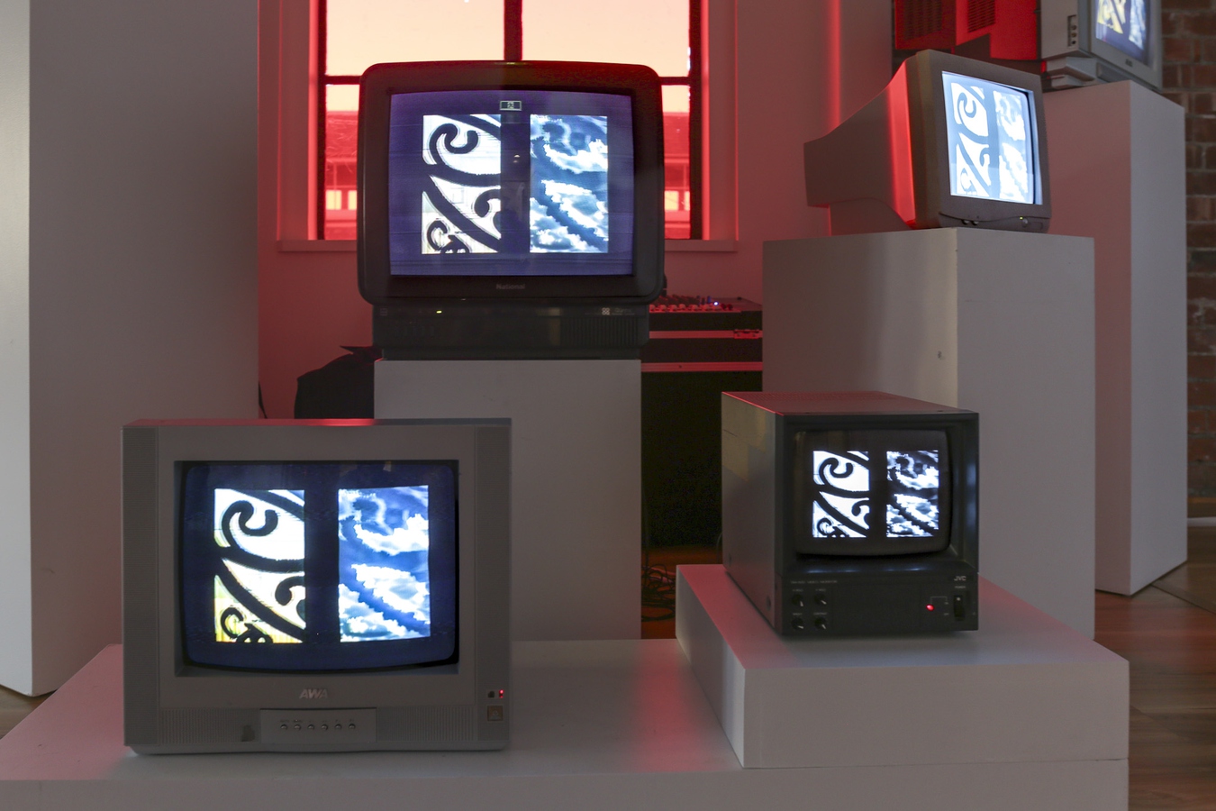 detial of view two CRT monitors playing video with red light from behind.