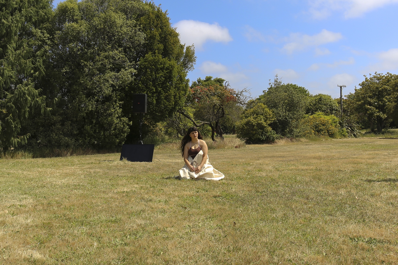 Ella kneeling on the grass with her canvas wrapped around her